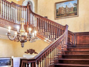 Eine prächtige Treppe mit aufwendigen Holzschnitzereien und einer Kristalllüster mit vielen Kerzen.