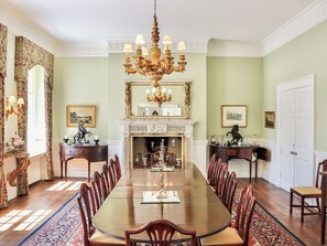 Una sala da pranzo formale con un grande tavolo di legno, un lampadario elaborato e un'arredamento classico.