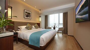 A hotel room with a bed, bedside table, lamp, and a painting on the wall.