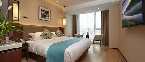 Una habitación de hotel con cama, mesita de noche, lámpara y un cuadro en la pared.