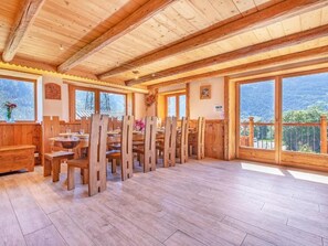 A wooden interior with a high ceiling, large windows, and a dining area with wooden chairs and tables. - Chalet Farmhouse by Interhome (Villaroger)