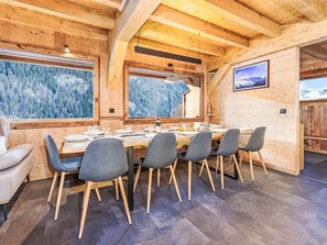 Un interno in legno con un tavolo da pranzo apparecchiato per sei, circondato da sedie con gambe di legno.