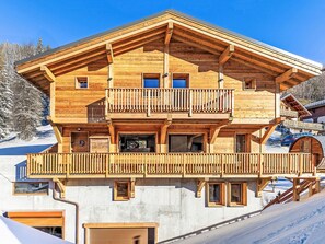 Eine mehrstöckige Holzhütte mit Balkonen, großen Fenstern und einer Garage.