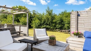A wooden deck with outdoor furniture, including a sofa, chairs, and a table.