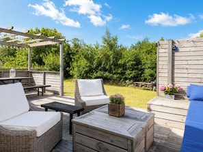 A wooden deck with outdoor furniture, including a sofa, chairs, and a table.