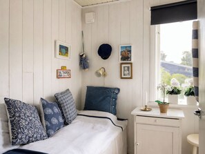 A bedroom with a bed, pillows, a dresser, a window with curtains, and wall decorations.