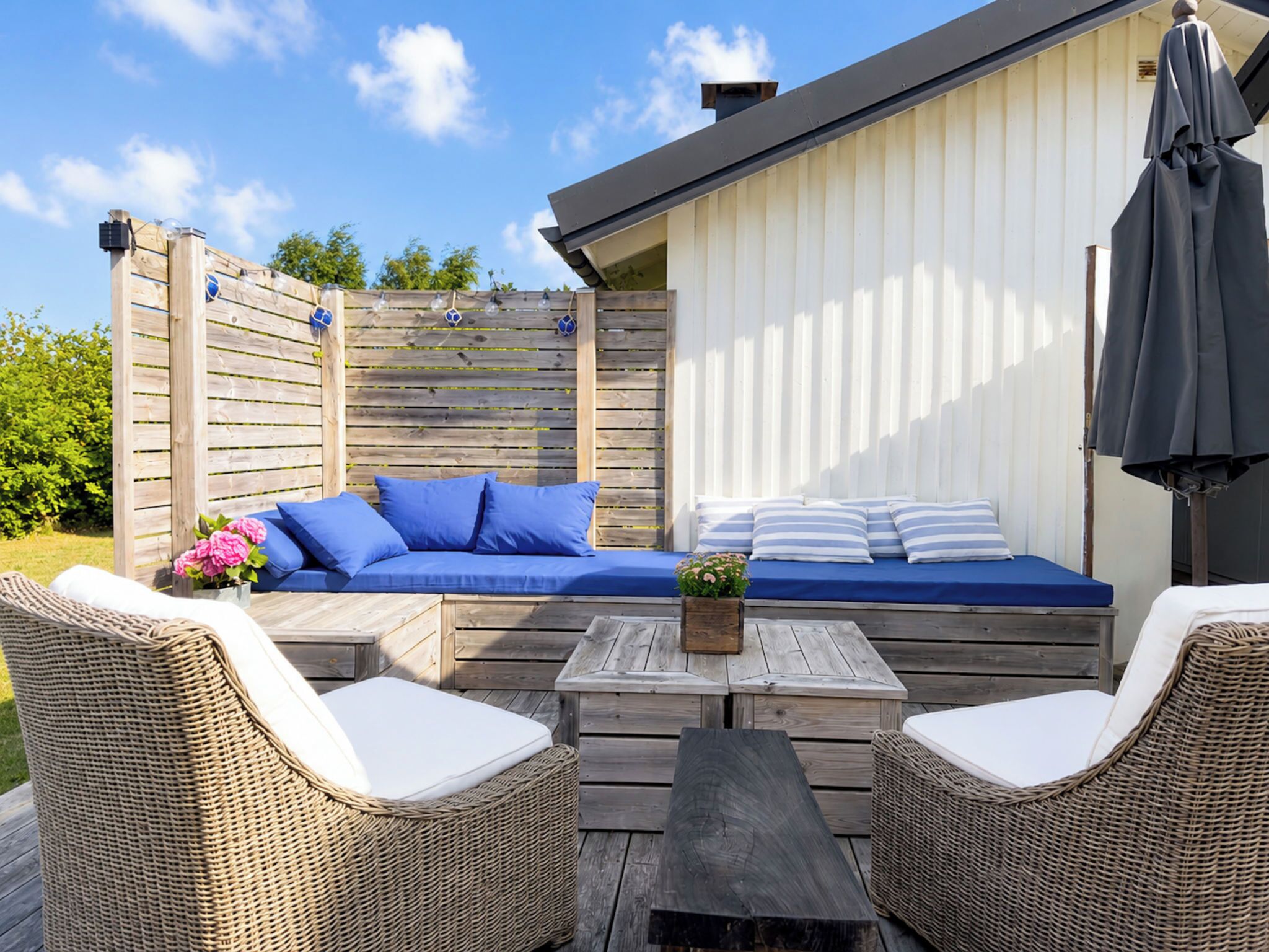 An outdoor seating area with a sofa, two wicker chairs, and a table.