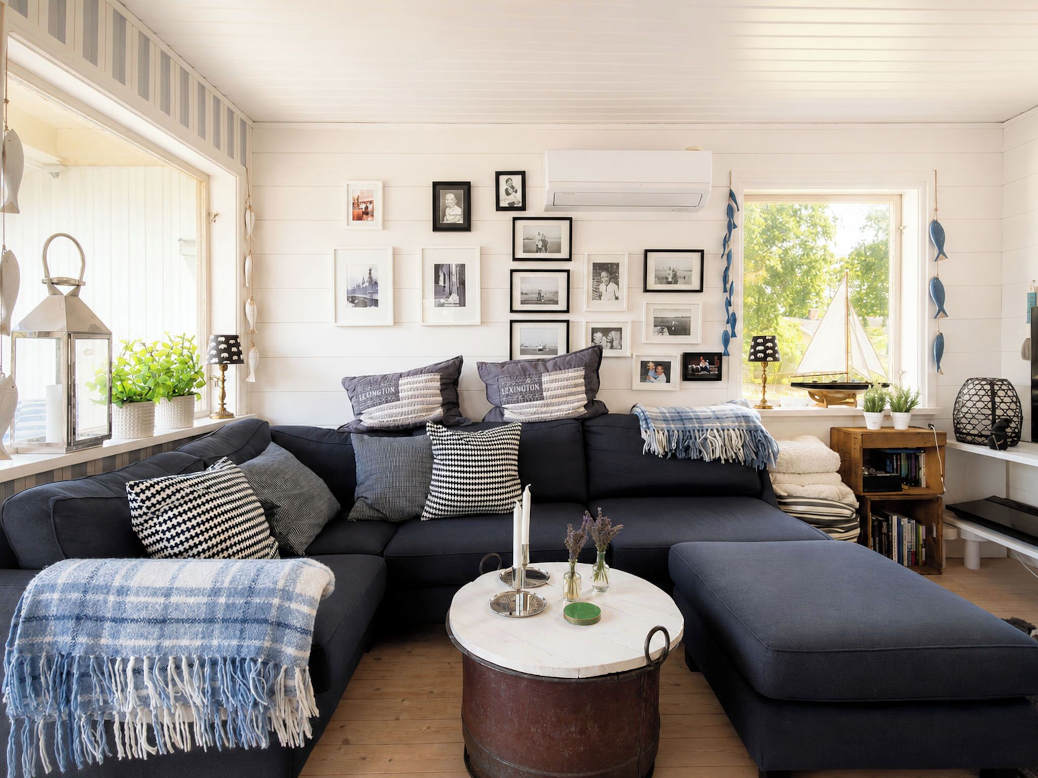 A modern living room with a sectional sofa, a round coffee table, and a large window with a view of greenery.