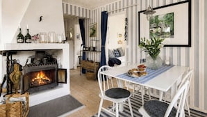A cozy room with a fireplace, striped wallpaper, and a dining area with a table and chairs.