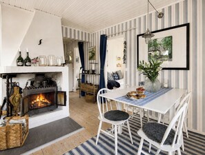 A cozy room with a fireplace, striped wallpaper, and a dining area with a table and chairs.