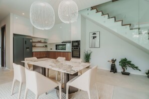 Eine moderne Küche mit Einbauofen, ein Essbereich mit Marmortisch und eine Treppe, die zu einer oberen Ebene führt.