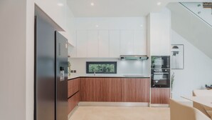 Eine moderne Küche mit Einbauofen, Kühlschrank und Essbereich mit Tisch und Stühlen.