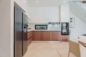 Eine moderne Küche mit Einbauofen, Kühlschrank und Essbereich mit Tisch und Stühlen.