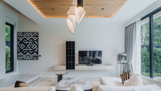 Ein modernes Wohnzimmer mit einer Sofagarnitur, einem Fernseher und einer Pendelleuchte.