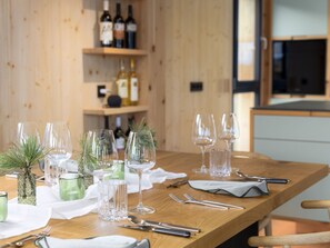 A wooden dining table set with wine glasses, cutlery, and a small potted plant. - 03_NTH032_Deluxe Chalet mit Sauna und Hot Tub by Interhome (Großveitsch)