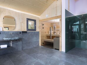 A modern bathroom with a stone sink, wooden walls, and a glass shower enclosure. - 03_NTH032_Deluxe Chalet mit Sauna und Hot Tub by Interhome (Großveitsch)
