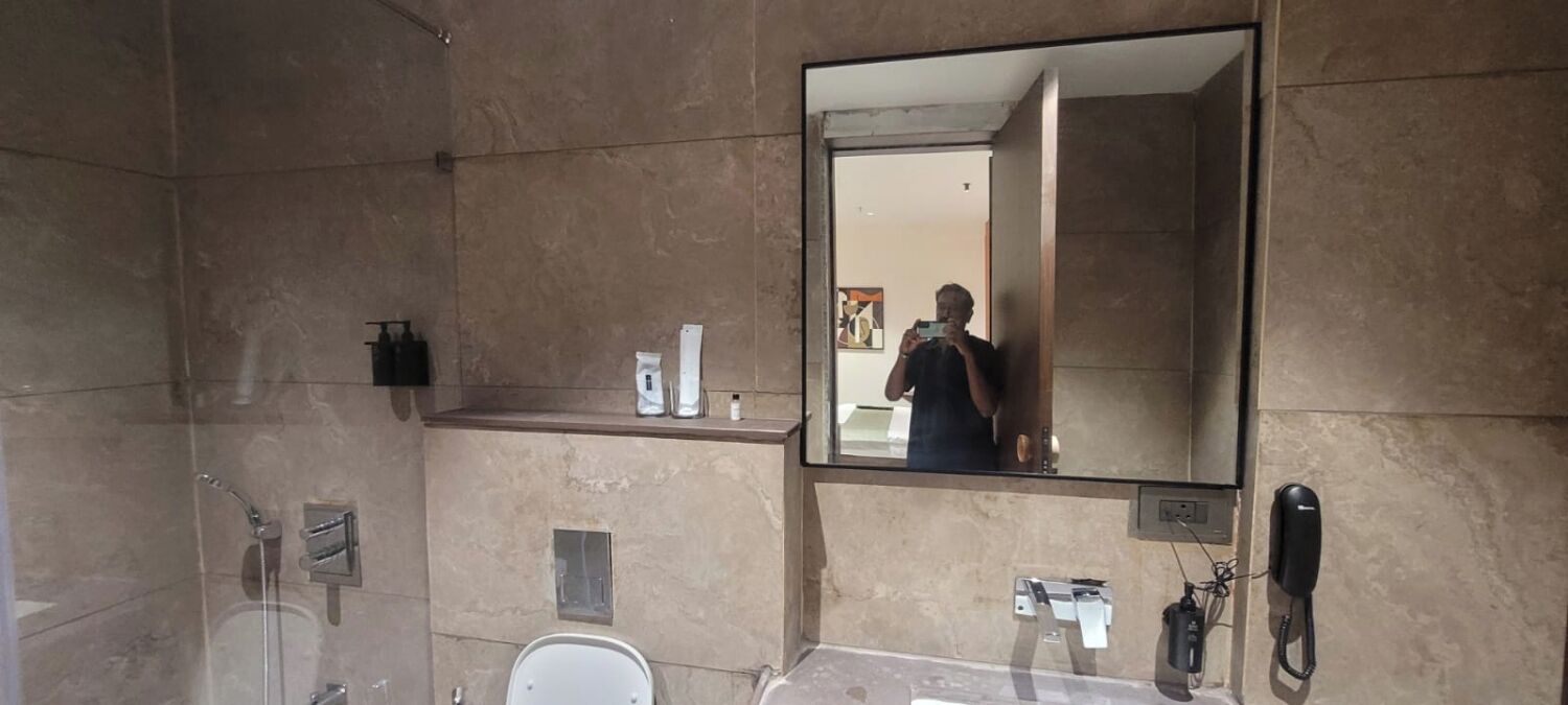 A bathroom with a shower, toilet, and a large mirror.