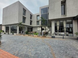 Un edificio moderno con patio, ventanas amplias y mesas al aire libre.