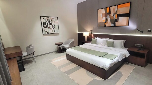 Une chambre d’hôtel moderne, dotée d’un grand lit, de tables de chevet, d’un bureau et de chaises.