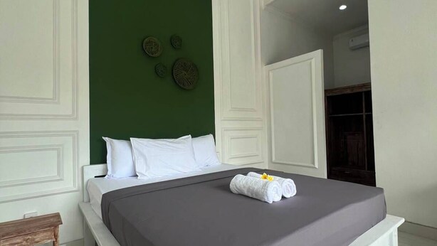 A modern hotel room with a large bed, white walls, and a green accent wall. - private room with bigger size room, near central canggu,
10minute to the beach (badung)