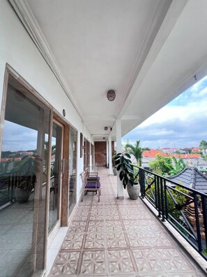 A balcony with a patterned floor, a seating area with chairs, and a view of the surrounding area. - private room with bigger size room, near central canggu,
10minute to the beach (badung)