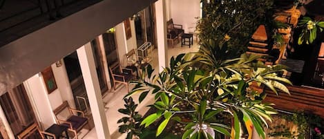 An indoor courtyard with a green lawn, seating area, and potted plants.