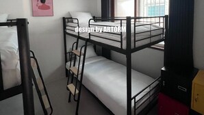 Et værelse med køjeseng, et vindue, en loftsvift og et lille skrivebord med stol.