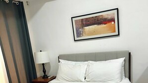 Una cama bien hecha con un cabecero gris, ropa de cama blanca y un toque de color turquesa.
