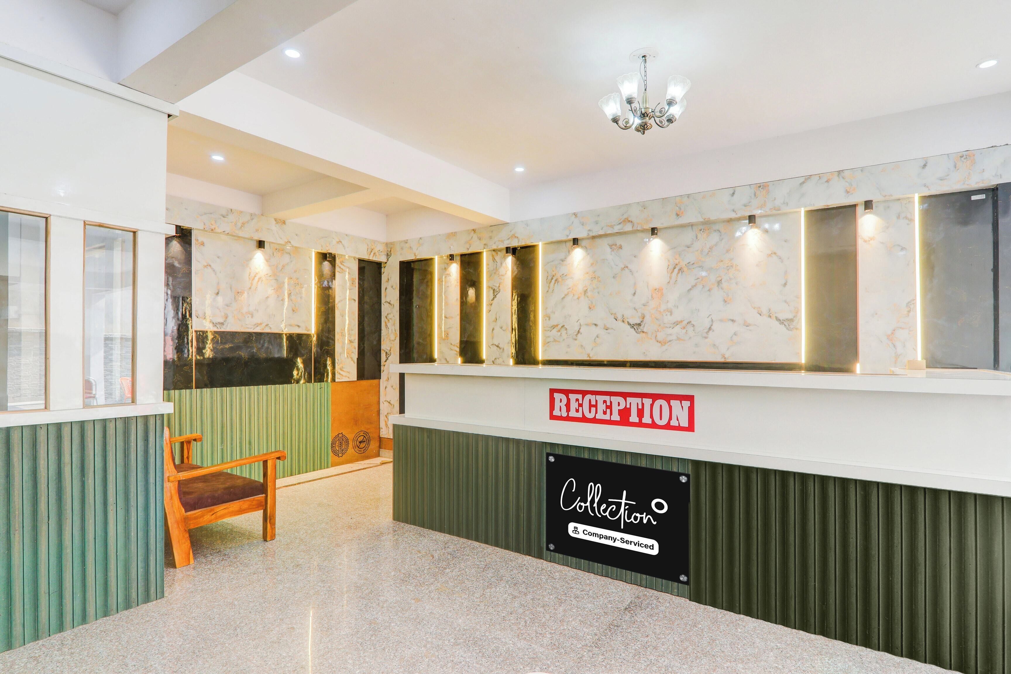A reception area with a marble wall, a reception desk, a chandelier, and a wooden chair.