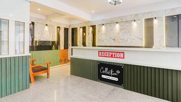 A reception area with a marble wall, a reception desk, a chandelier, and a wooden chair.