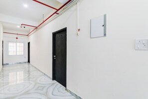 A hallway with a black door, white walls, and a patterned floor.