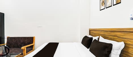 A hotel room with a bed, a chair, a table, and a television.