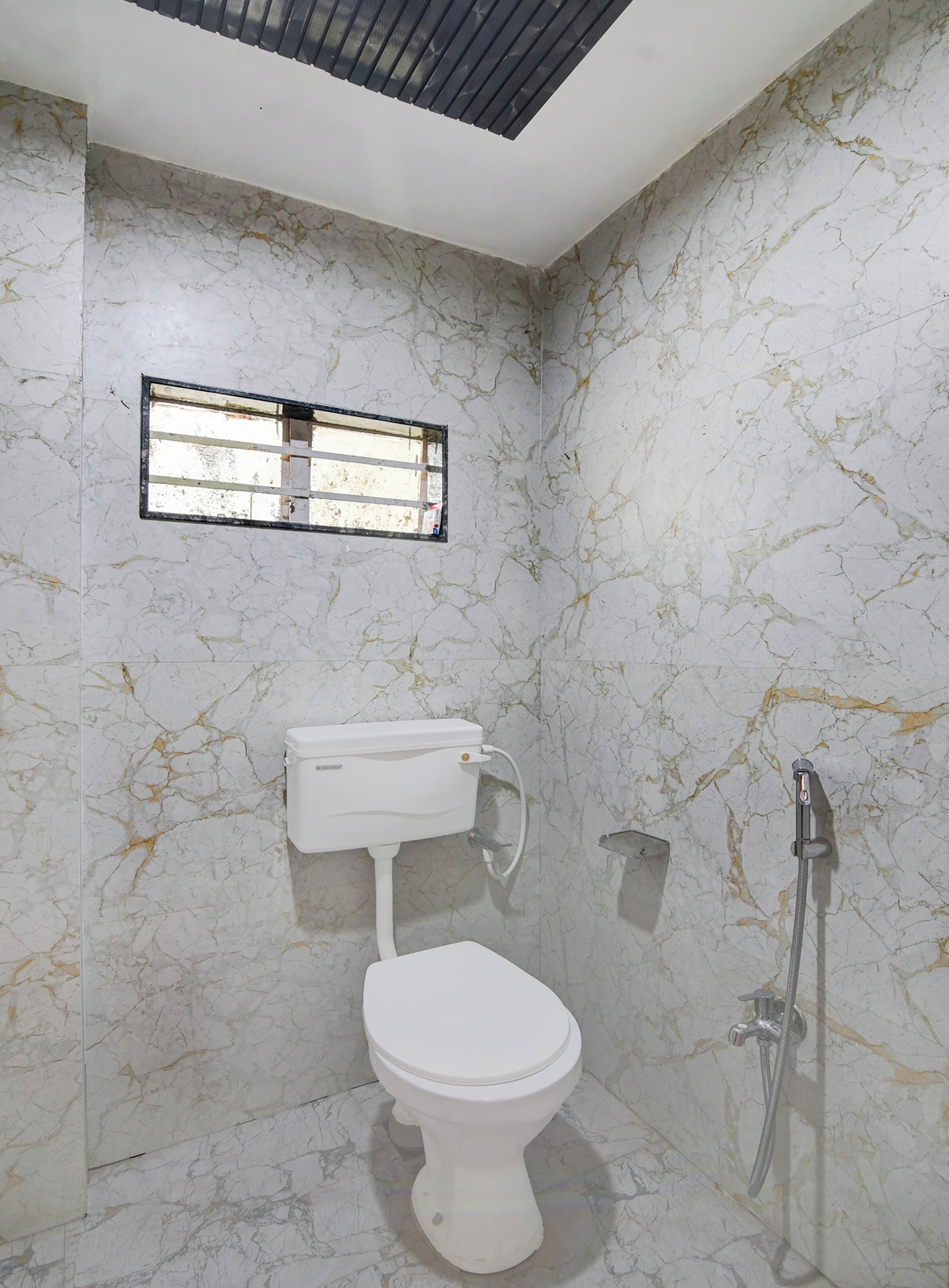 Un baño con inodoro, ducha y ventana.