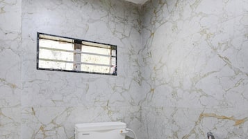 Un baño con inodoro, ducha y ventana.