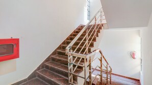 Eine Treppe mit Metallgeländern und Holzstufen, die zu einer Empore mit einem Fenster führt.