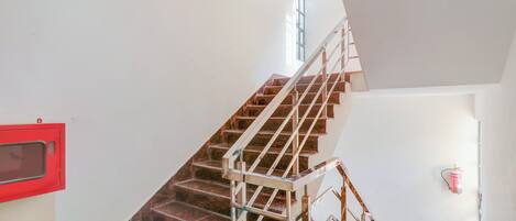 Eine Treppe mit Metallgeländern und Holzstufen, die zu einer Empore mit einem Fenster führt.