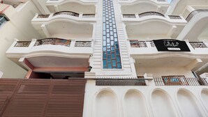 A multi-story building with balconies, a central vertical feature, and a sign indicating a company service. - Super Collection O Nagwa Lanka Varanasi (Varanasi)