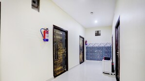 A corridor with doors, a fire extinguisher, and a tiled wall. - Super Collection O Nagwa Lanka Varanasi (Varanasi)
