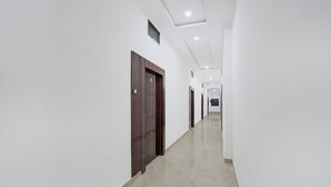 A long, narrow hallway with white walls and a polished floor, leading to multiple doors. - Super Collection O Banaras Railway (Varanasi)