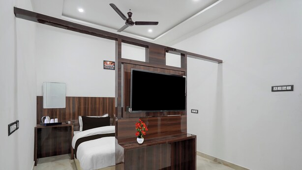 A hotel room with a bed, bedside table, TV, and a ceiling fan. - Super Collection O Banaras Railway (Varanasi)