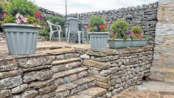 A stone staircase leading to a seating area with potted plants and plastic chairs.