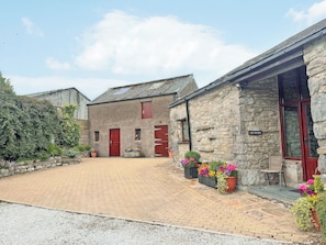 A stone building with red doors and a paved courtyard. - 2 steps to entrance. (Settle)