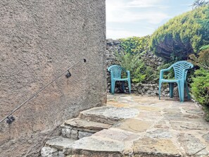 A stone staircase leading to a seating area with two blue plastic chairs.