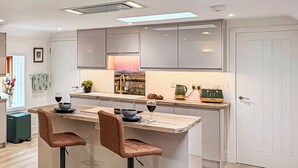 Una cocina moderna con una isla central, taburetes de bar y vistas al área de estar.