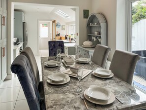 A dining area with a marble table set for four, surrounded by upholstered chairs. - White House by the Sea (Withernsea)