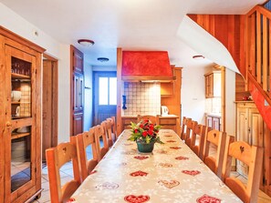 A dining area with a long table, wooden chairs, and a central flower arrangement. - Paradis de St.Martin by Interhome (Les Granges)