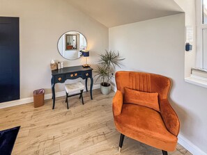 A room with a dark blue vanity, a round mirror, a potted plant, and an orange armchair. - 1 bedroom accommodation in Manfield, near Darlington (Manfield, near Darlington)