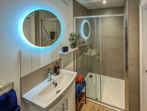 A bathroom with a white sink, a mirror with a blue light, a glass shower enclosure, and a towel rack. - 1 bedroom accommodation in Manfield, near Darlington (Manfield, near Darlington)