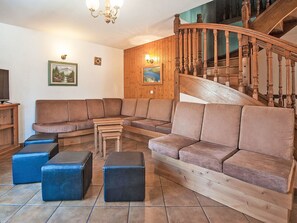 Ein Wohnzimmer mit einer Holztreppe, einem Ecksofa und einem Fernseher.