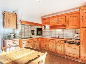 A kitchen with wooden cabinets, a microwave, a stove, and a dishwasher. - Flocon de Belleville by Interhome (Les Granges)